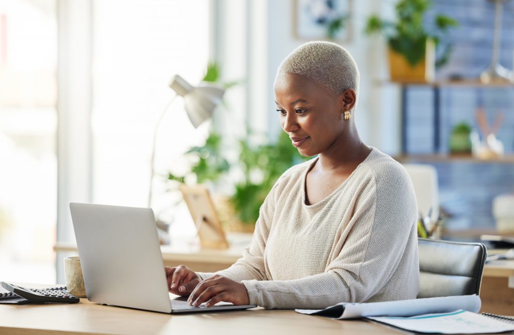 Laptop, business and black woman typing, accountant and working on web project in office workplace. Auditor, computer and African female professional bookkeeper writing email, report or research.