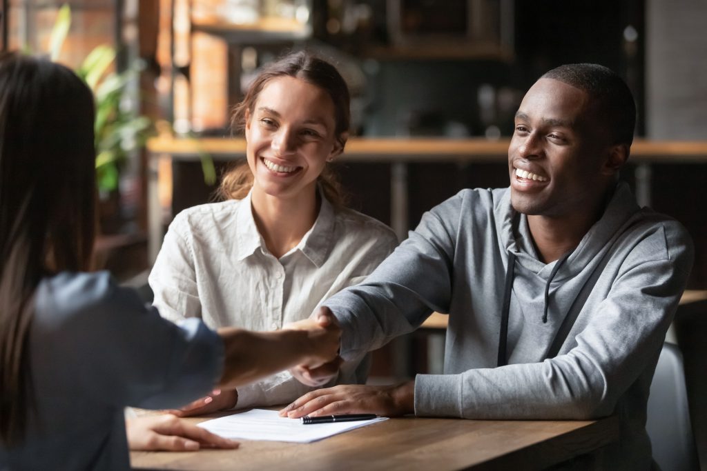 Happy interracial couple handshake bank manager take mortgage loan