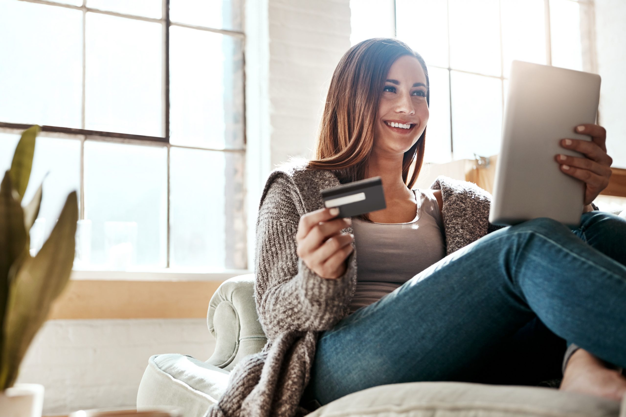 Online shopping, credit card and woman with digital tablet on a sofa, relax and smile while checking booking online. Ecommerce, girl and card for banking, credit score or subscription in living room