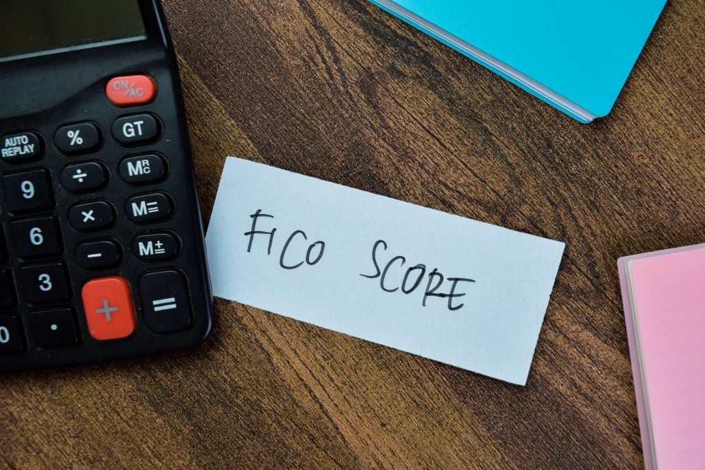 Concept of Fico Score write on sticky notes isolated on Wooden Table.