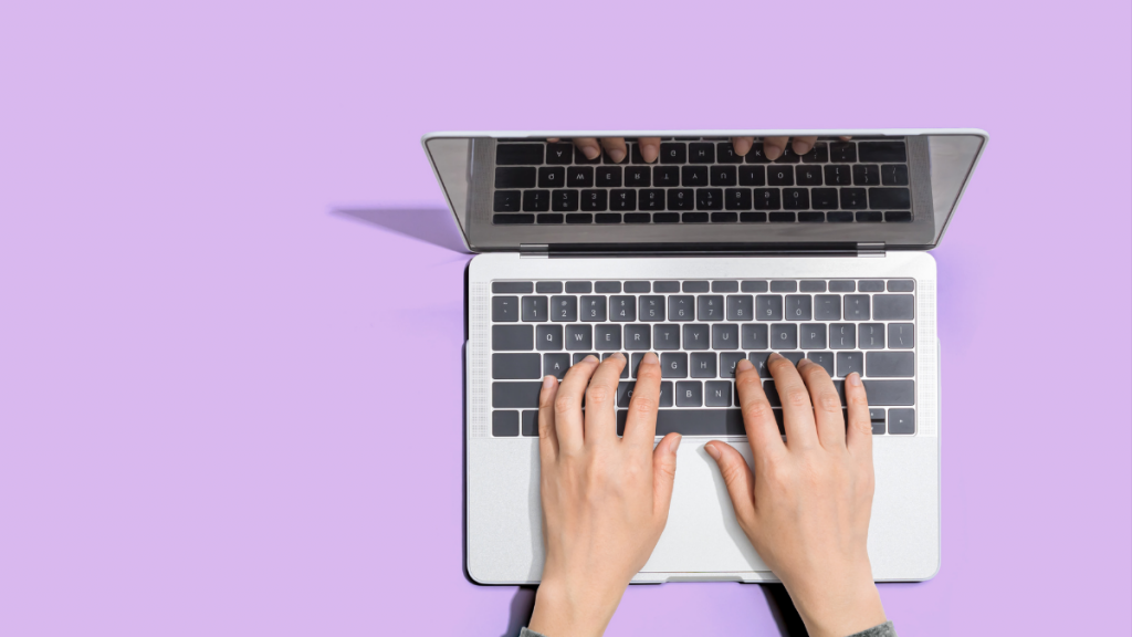 hands on a laptop with a lavender background
